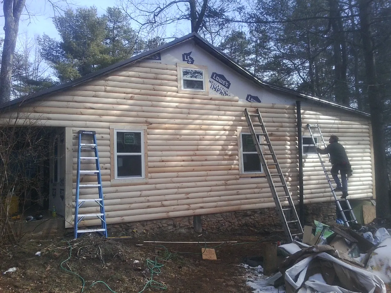 Ladders set against fresh log siding during an exterior remodel in Emerson