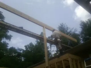 Carpenter setting a ridge beam over a new addition frame — Ice Dam Removal by Roofing Brothers in Emerson