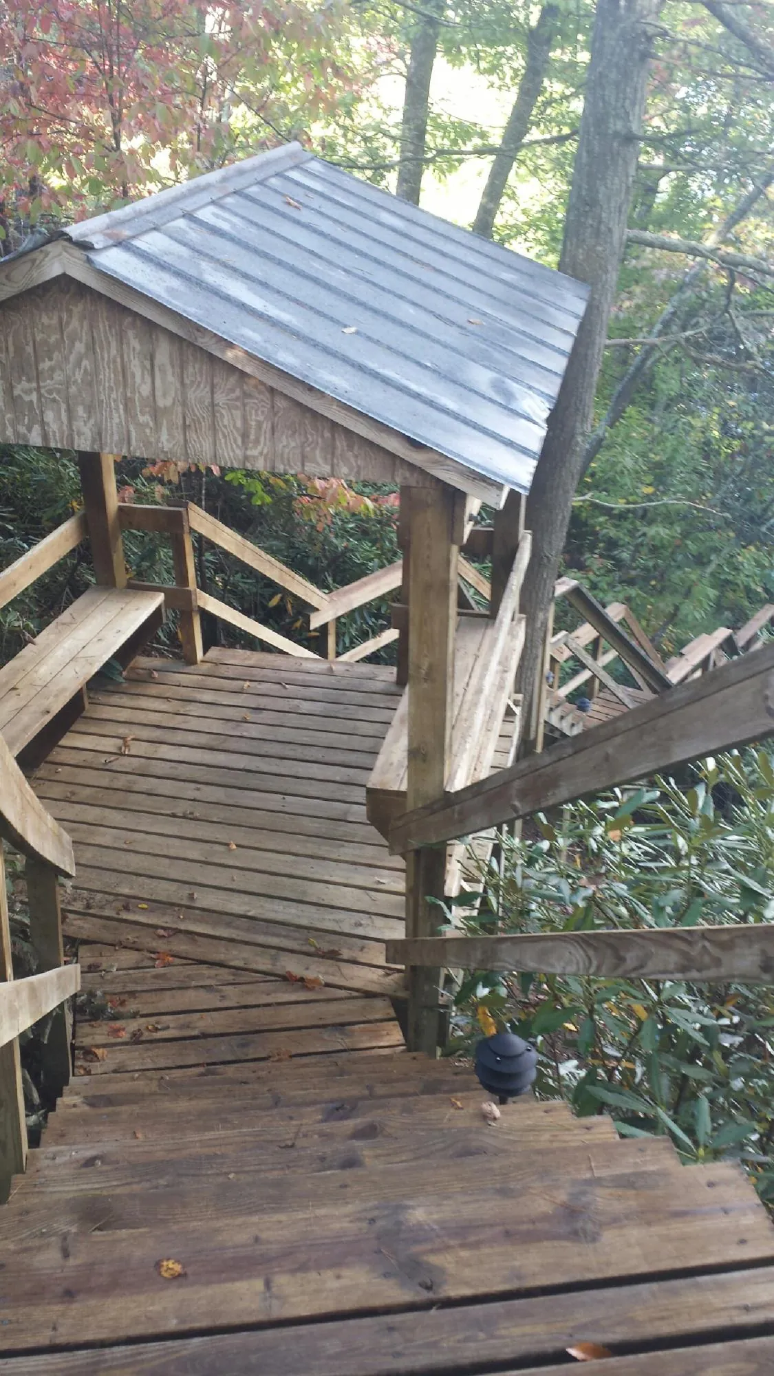 Metal roofed shelter over wooden steps on a wooded walkway — Skylight Repair & Installation work by our crew in Emerson
