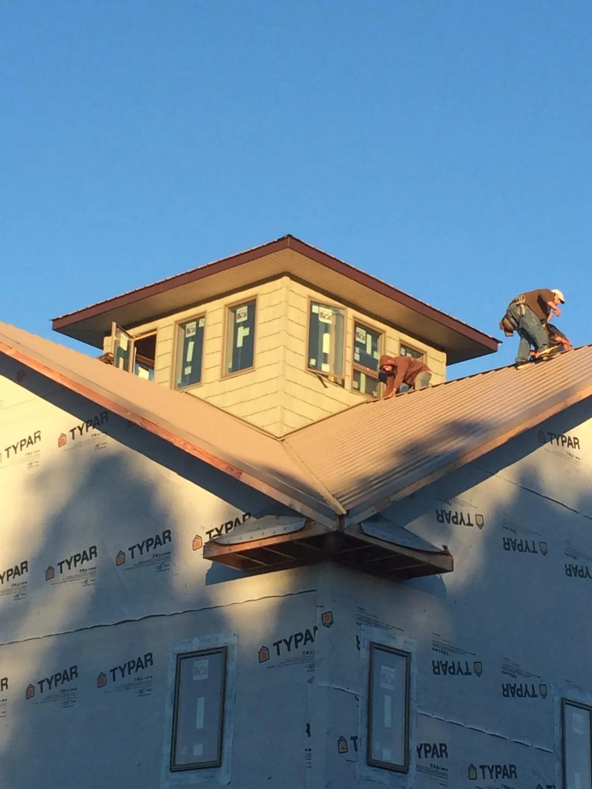 Roofers working around a rooftop cupola on a new metal roof at sunset — Roof Waterproofing in Emerson by Roofing Brothers